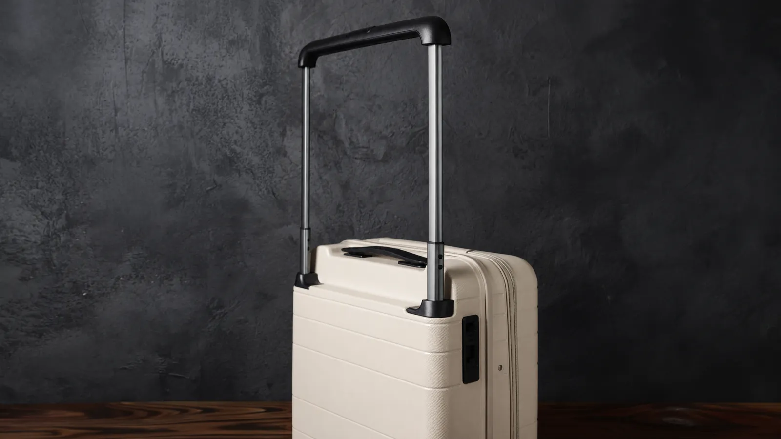 The Vasy carry-on from behind, telescopic handle extended, in the dark studio.