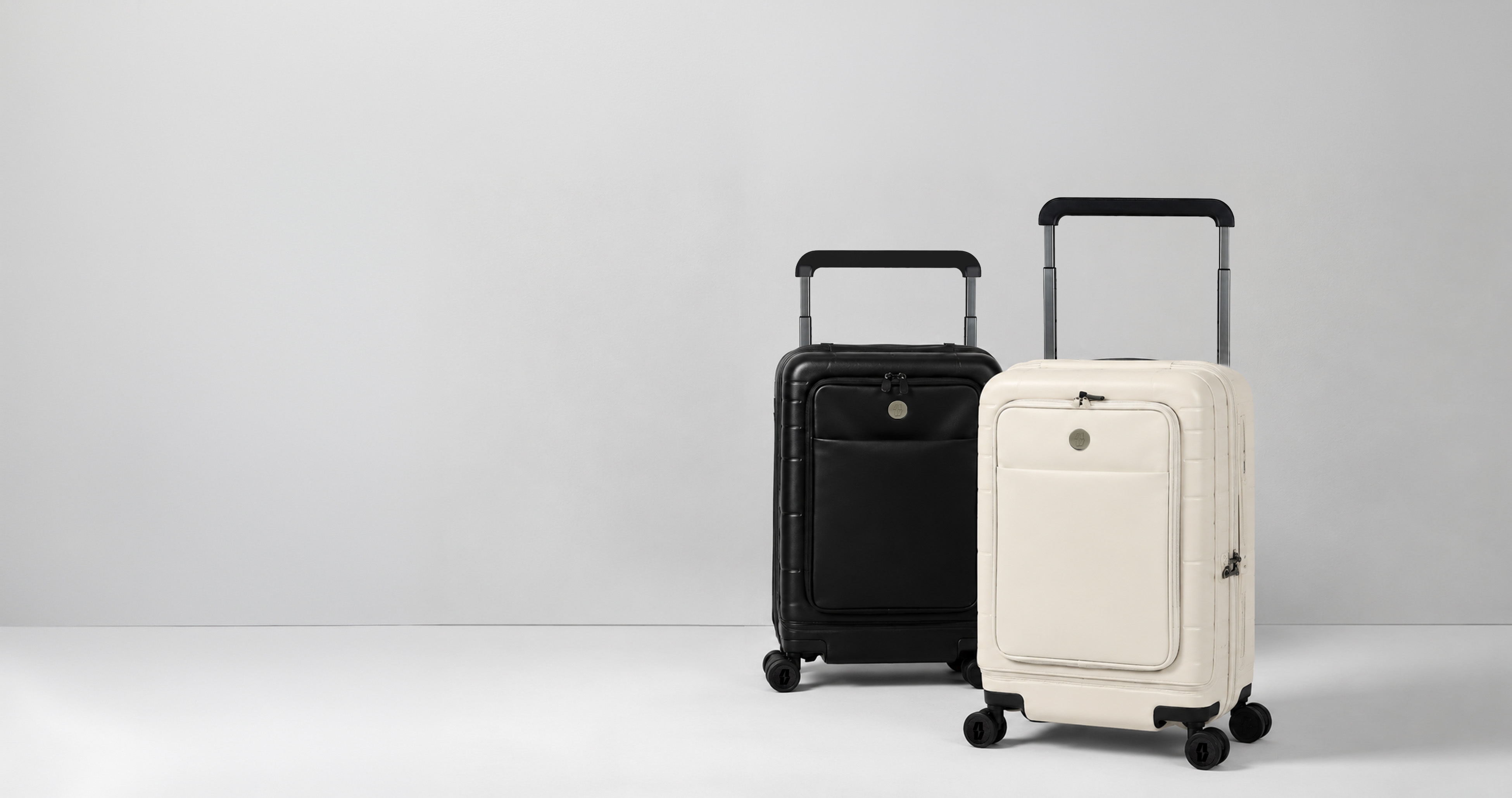 Midnight-black and oat-cream Vasy carry-ons stand together in a clean studio.